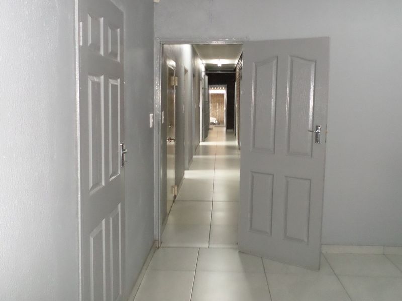 A functional hallway featuring tiled flooring and multiple panelled interior doors, providing access to various rooms within the industrial property.
