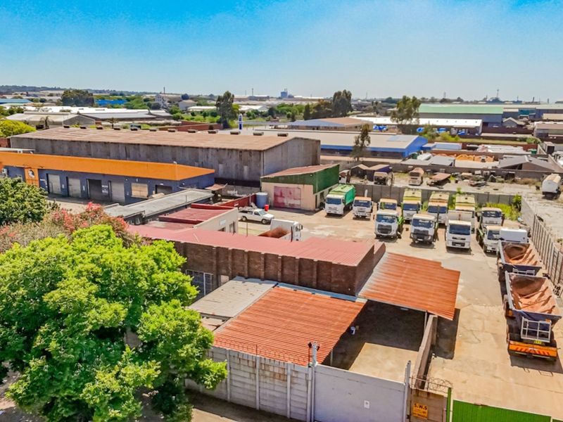 Aerial view of an industrial property featuring a warehouse facility, paved yard space, and secure perimeter walling in an established industrial precinct.