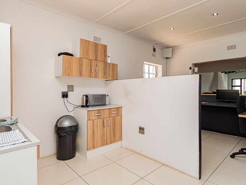 Open plan kitchen and workspace area featuring tiled flooring, built-in cabinetry, and a functional partition wall separating the zones.