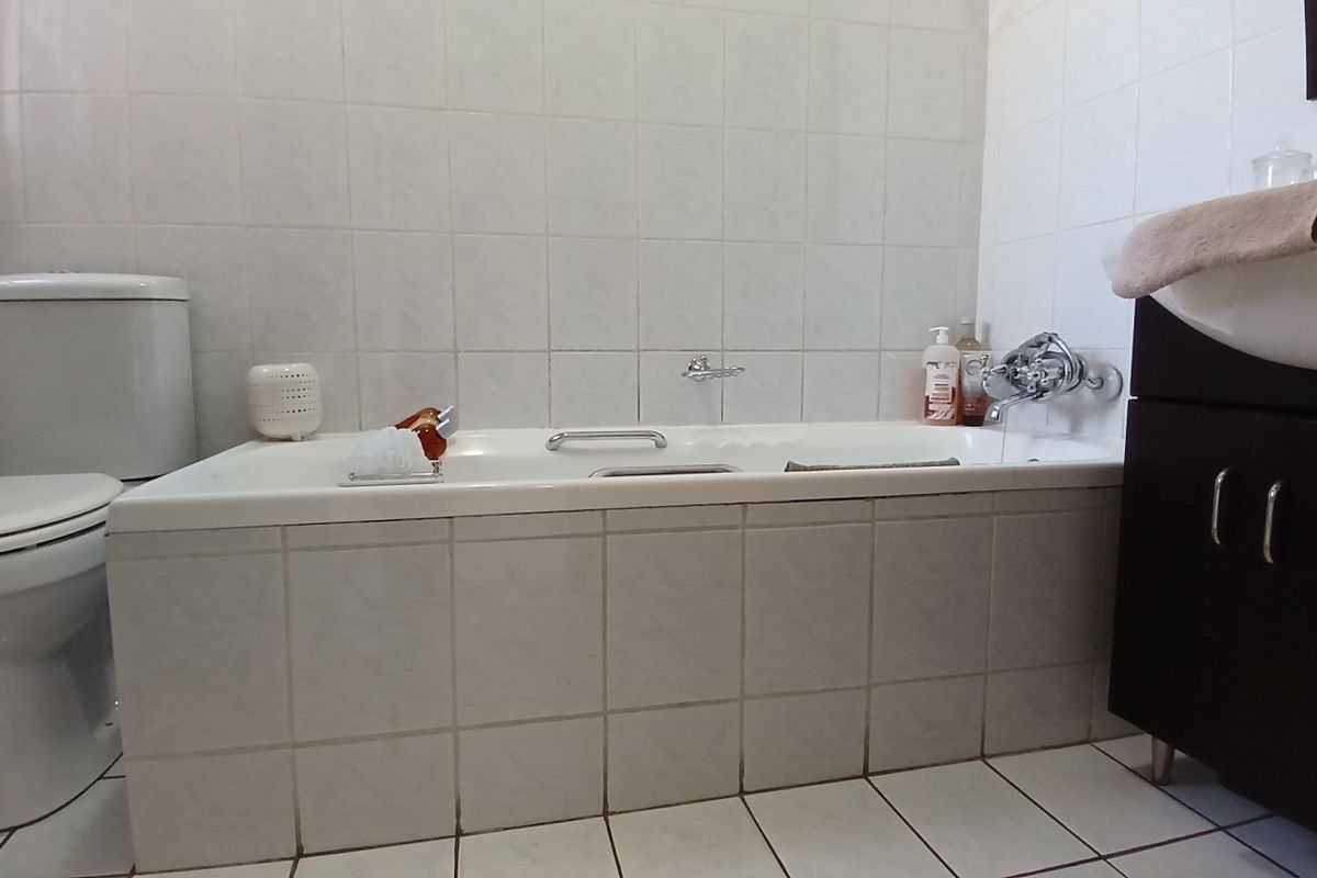 A functional bathroom featuring a built-in bathtub, a standard toilet, and a vanity cabinet with a basin.