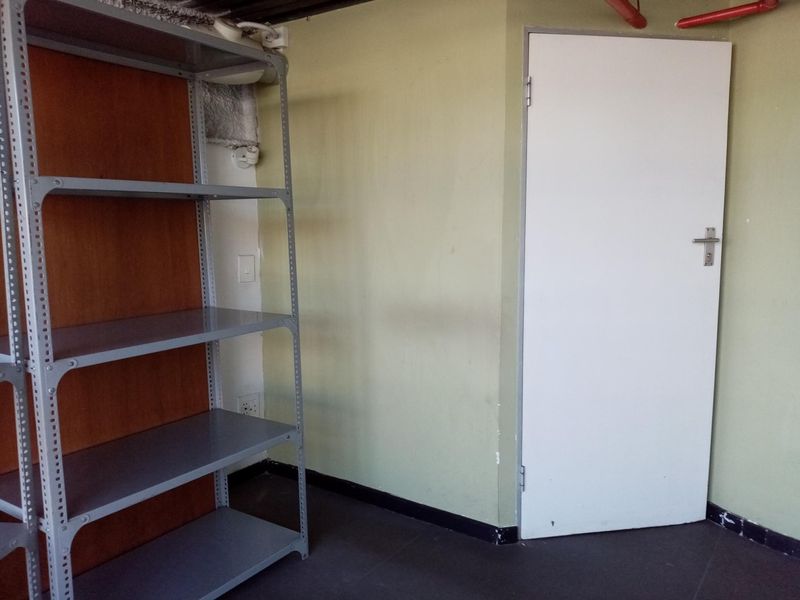 A functional utility or storage space featuring exposed fire safety piping, a standard internal door, and basic wall finishes.