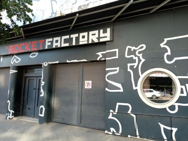 Front facade of a commercial property featuring security roller shutters, a circular window, and distinctive exterior mural signage.