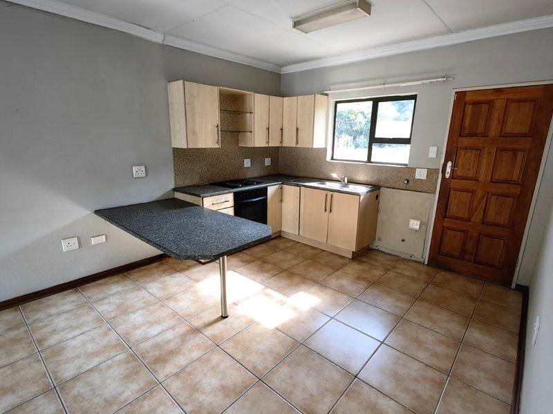 An empty kitchen featuring light wood cabinetry, a breakfast bar, integrated oven and hob, and ceramic tiled flooring, requiring minor cosmetic finishing.