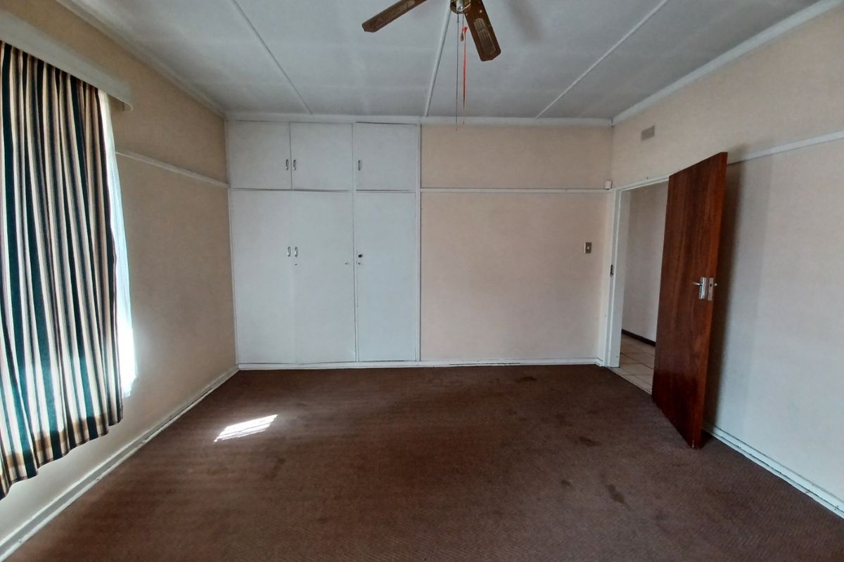 An empty bedroom featuring built-in cupboards, a ceiling fan, and carpeted flooring, offering a blank canvas for renovation or restyling.
