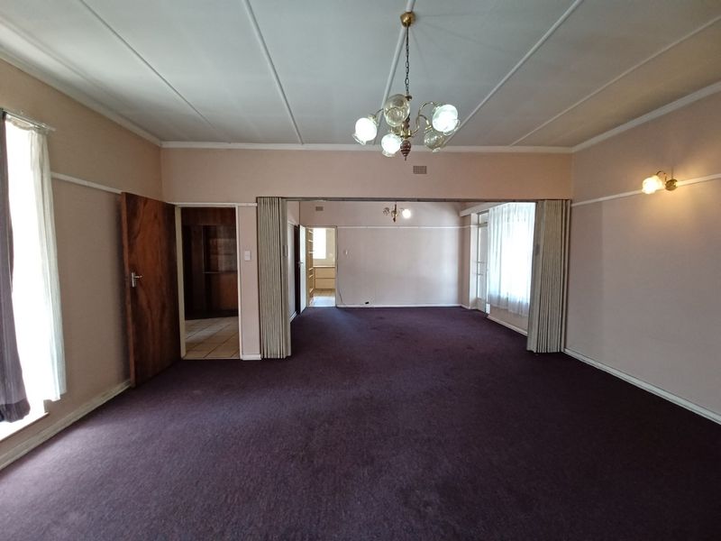 Spacious living area featuring a folding room divider, classic chandelier lighting, and wall sconces, offering a versatile layout with neutral wall tones.
