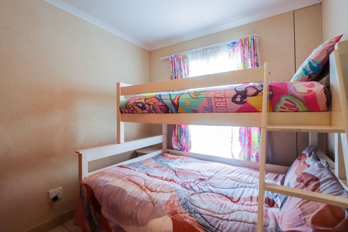 A functional bedroom featuring neutral wall finishes and a window with curtain tracks.