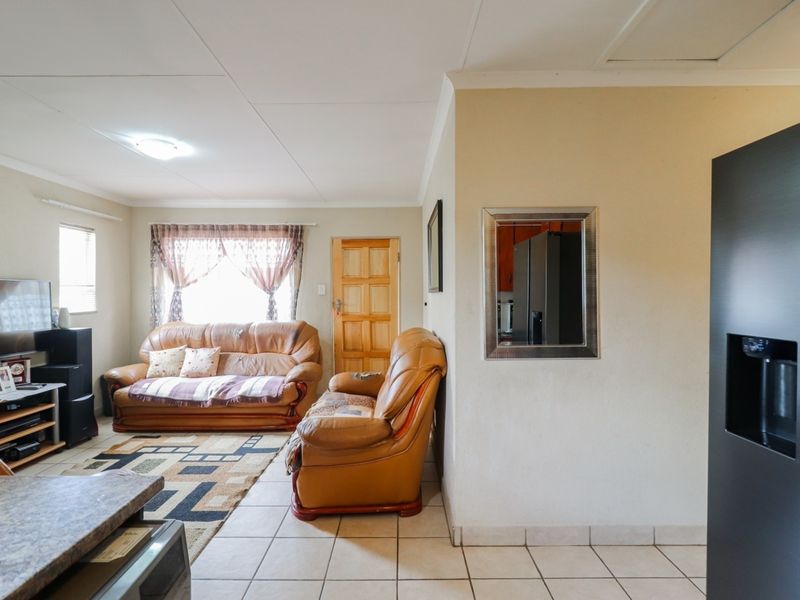 Open plan living area featuring tiled flooring, neutral wall finishes, and a timber entrance door, providing a functional and connected living space.