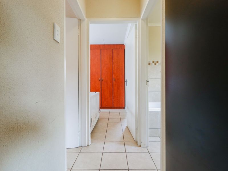 A functional hallway featuring tiled flooring, providing access to adjacent bedrooms and a bathroom with built-in storage cabinetry.