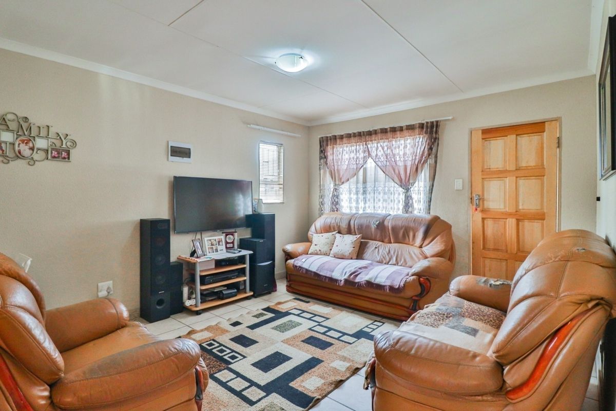 A functional living room featuring tiled flooring, a timber panel door, and neutral wall finishes, providing a comfortable and practical space for relaxation.