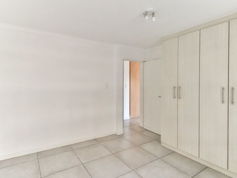 A bright, empty bedroom featuring neutral tiled flooring and ample built-in cupboard storage, offering a clean and versatile space.