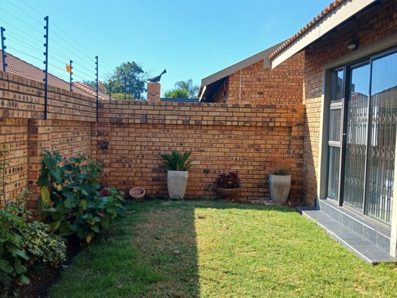 A private rear garden area featuring face brick boundary walls with electric fencing and direct access to the home via a sliding glass door.
