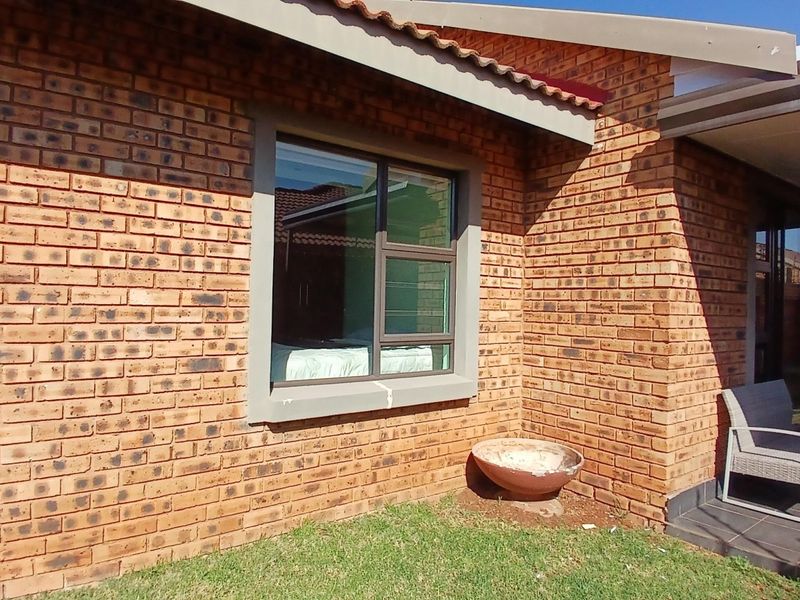 Rear exterior view of the cluster home featuring face brick construction, aluminium window frames, and a covered patio area.