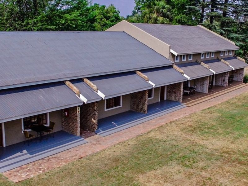 Aerial view of a residential apartment block featuring a corrugated metal roof, brick facade, and covered patio areas overlooking a lawn.