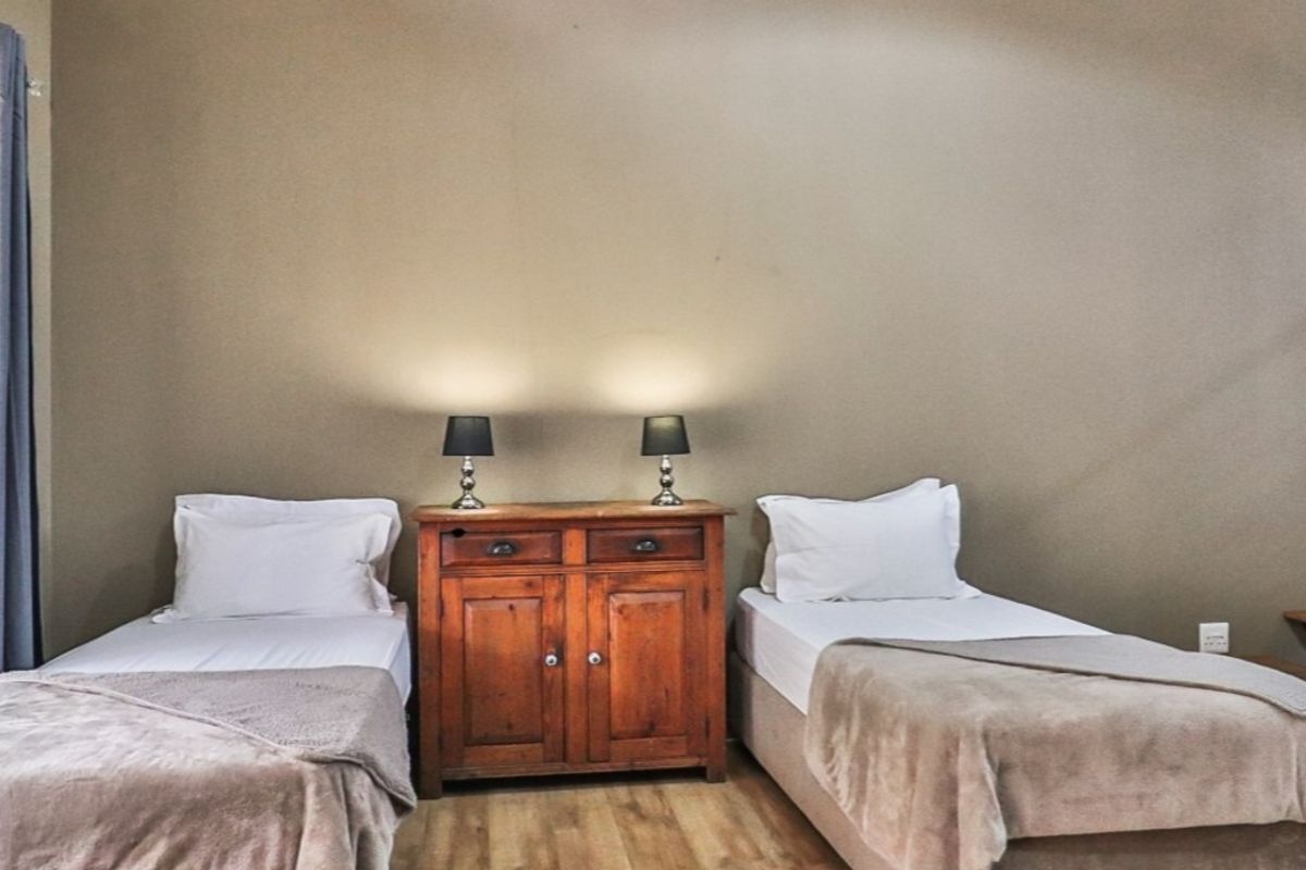 A bedroom featuring laminate flooring and an adjacent staircase, providing a functional sleeping space within the apartment.