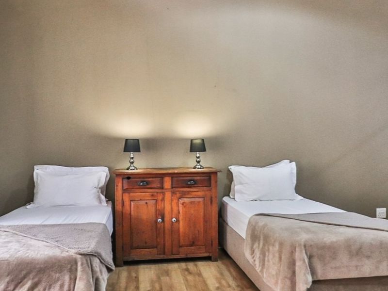 A bedroom featuring laminate flooring and an adjacent staircase, providing a functional sleeping space within the apartment.
