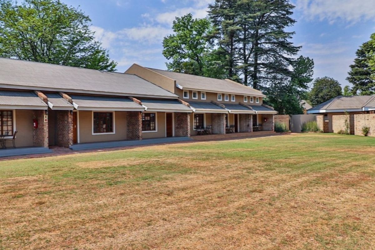 A view of the rear exterior of the apartment complex, featuring a long covered patio area and a spacious shared lawn.