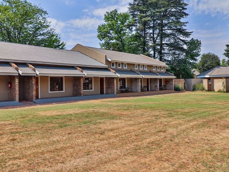 A view of the rear exterior of the apartment complex, featuring a long covered patio area and a spacious shared lawn.