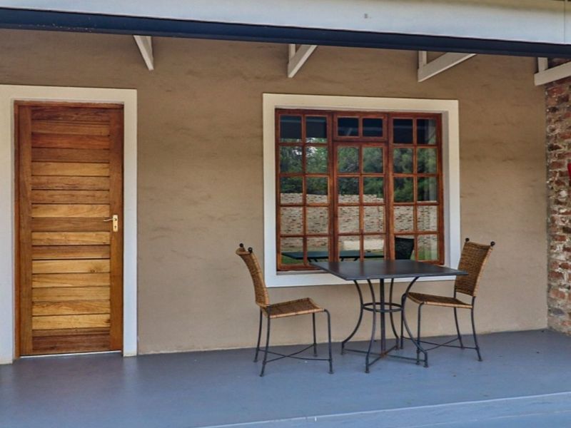 A covered patio area featuring a timber door, timber-framed window, and exposed brick accents, providing a functional outdoor space.