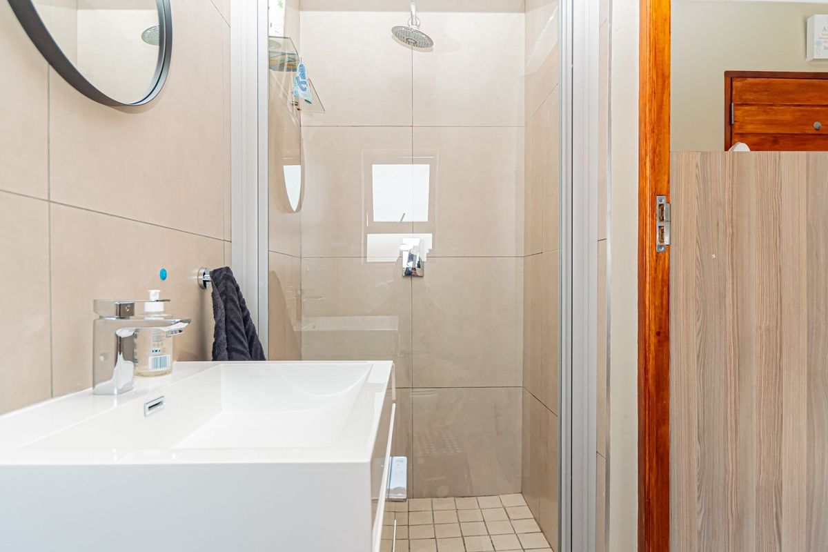Modern bathroom featuring a wall-mounted vanity basin with chrome mixer tap and a tiled walk-in shower enclosure.