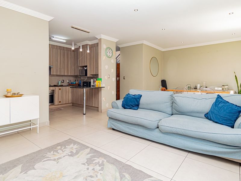Spacious open-plan living area featuring tiled floors, recessed lighting, and a modern kitchen with built-in cabinetry and a breakfast bar.