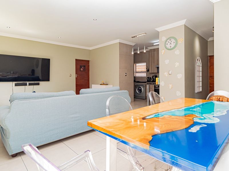 Spacious open-plan living and dining area featuring tiled floors, recessed lighting, and a seamless transition into the functional kitchen and laundry space.
