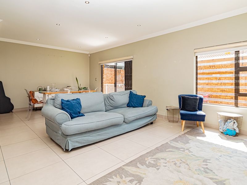 Spacious open-plan living area featuring neutral walls, tiled flooring, recessed lighting, and large windows providing ample natural light.