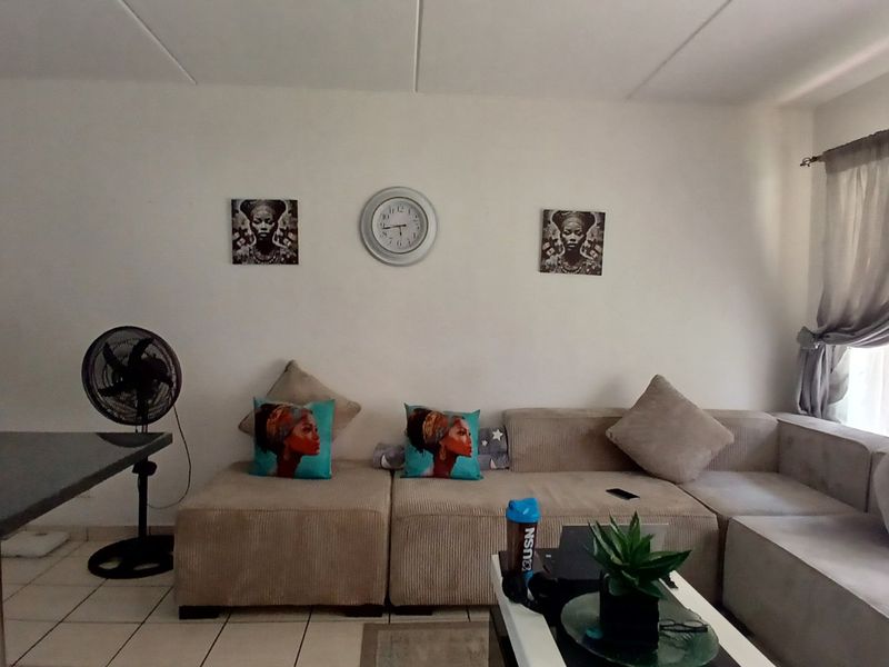 A living room area featuring tiled flooring and a window with curtain rod, providing a functional space for relaxation.