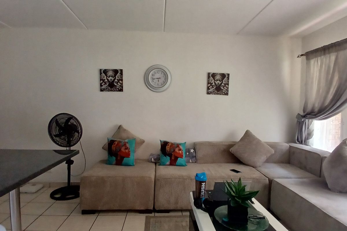 A living room area featuring tiled flooring and a window with curtain rod, providing a functional space for relaxation.