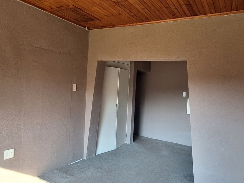 An empty bedroom featuring a timber ceiling and a built-in cupboard, offering a blank canvas for renovation or interior design updates.
