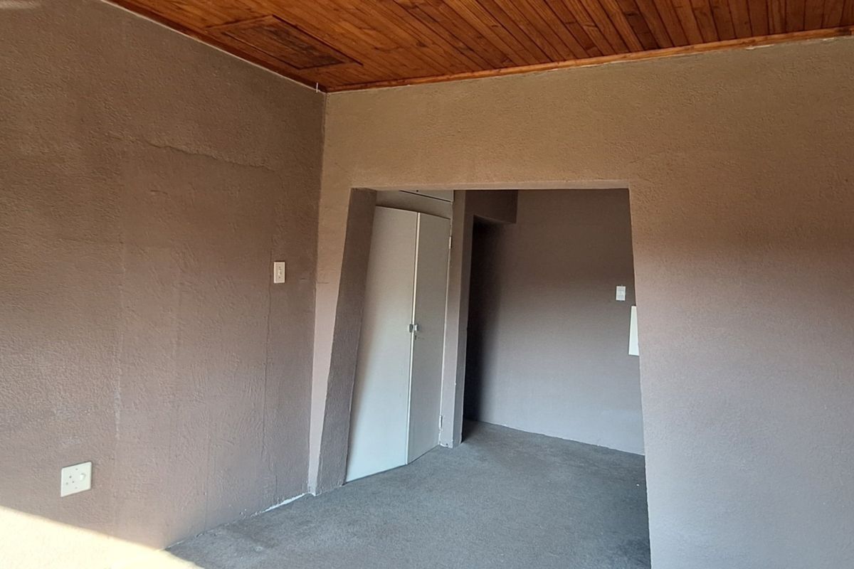 An empty bedroom featuring a timber ceiling and a built-in cupboard, offering a blank canvas for renovation or interior design updates.