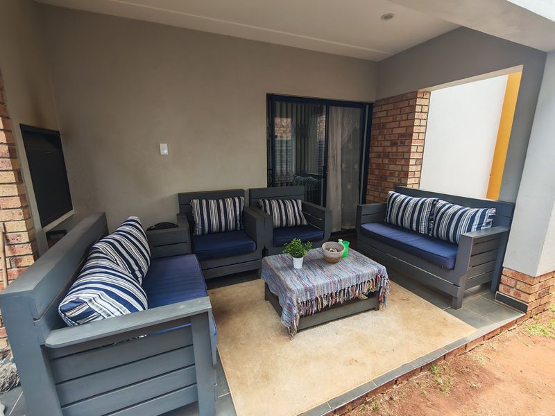 A covered patio area featuring exposed brick accents, tiled flooring, and direct access to the interior through a sliding glass door.