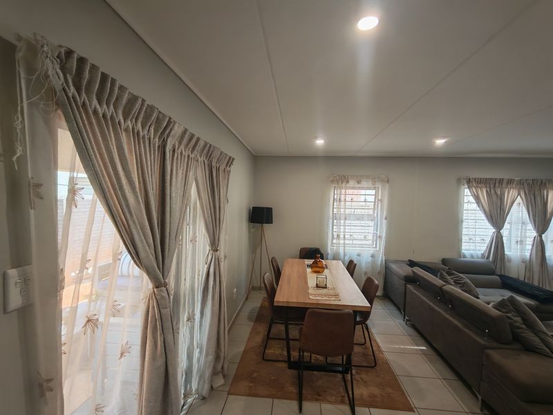 An open-plan living and dining area featuring tiled flooring, recessed lighting, and a sliding glass door providing access to the outdoor space.