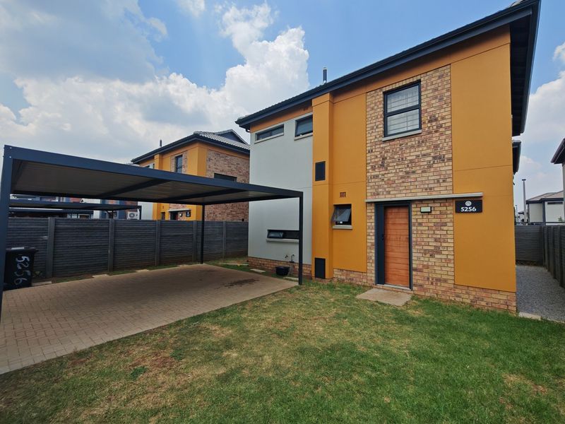 Modern two-story residential property featuring a brick and rendered facade, a covered carport, and a neat front lawn.