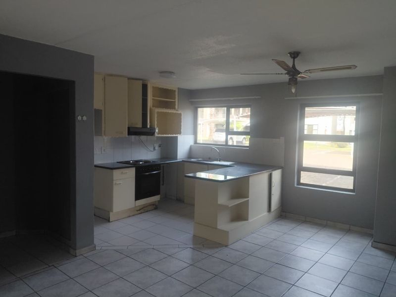 Open-plan kitchen featuring built-in cabinetry, electric stove, oven, and tiled flooring, offering a functional layout with natural light.