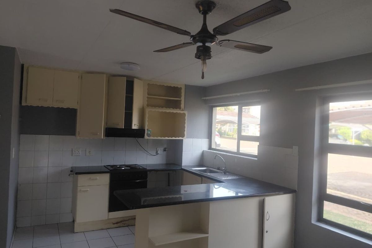 A functional kitchen featuring built-in cabinetry, a hob, oven, extractor fan, and a breakfast counter, with tiled flooring and backsplash throughout.