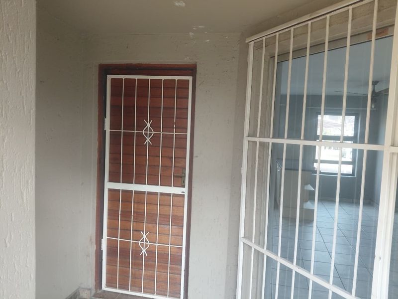 Entrance area featuring a wooden security gate and a sliding glass door leading into the apartment interior.