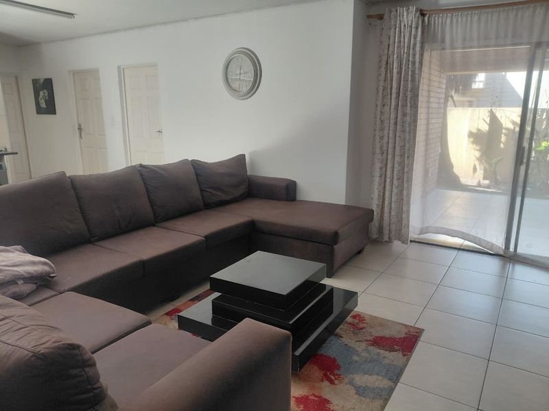 A spacious living room featuring neutral tiled flooring and a large sliding glass door providing direct access to the outdoor patio area.