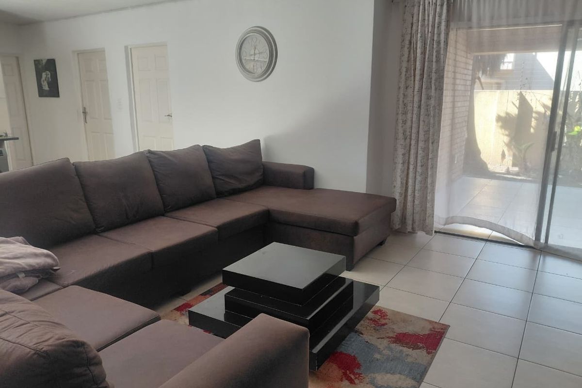 A spacious living room featuring neutral tiled flooring and a large sliding glass door providing direct access to the outdoor patio area.