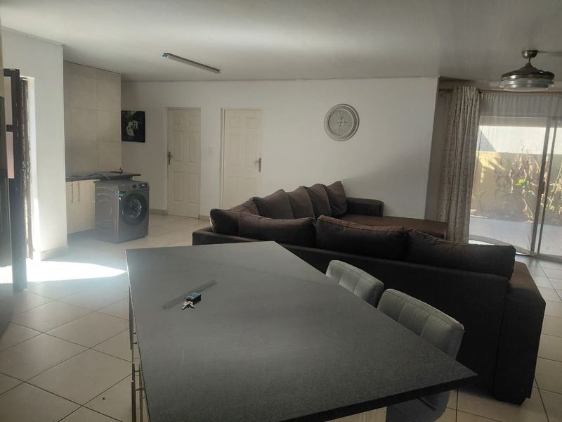 Open-plan living area featuring a kitchen with island, tiled flooring, and sliding glass doors leading to an outdoor space.