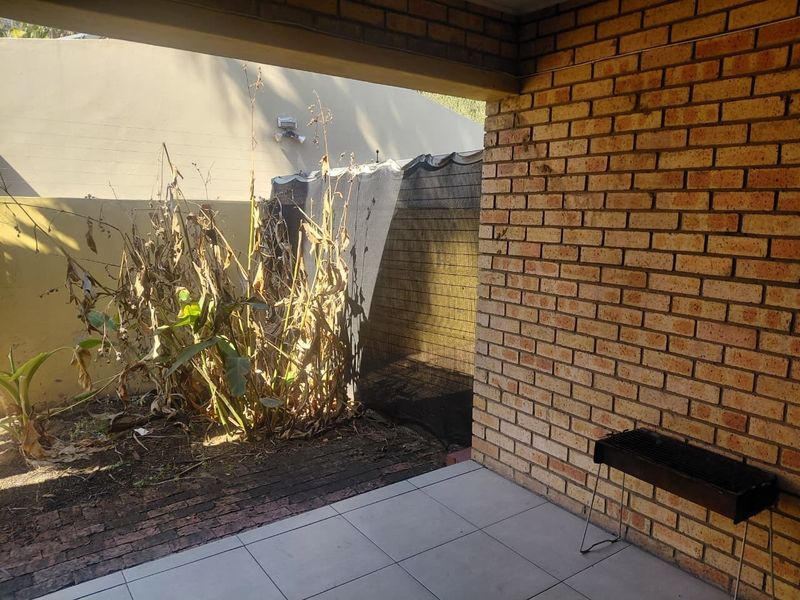 A covered brick patio area featuring tiled flooring, providing an outdoor space that requires landscaping and maintenance to improve its overall appeal.