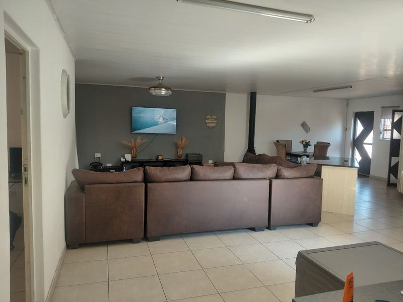 Spacious open-plan living area featuring tiled flooring, a feature accent wall, and a freestanding fireplace, offering a versatile layout for dining and relaxation.