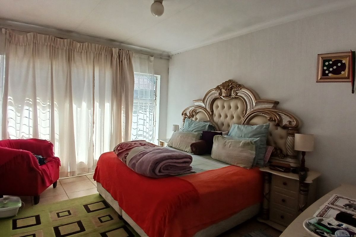 A bedroom featuring tiled flooring and a sliding glass door providing natural light.