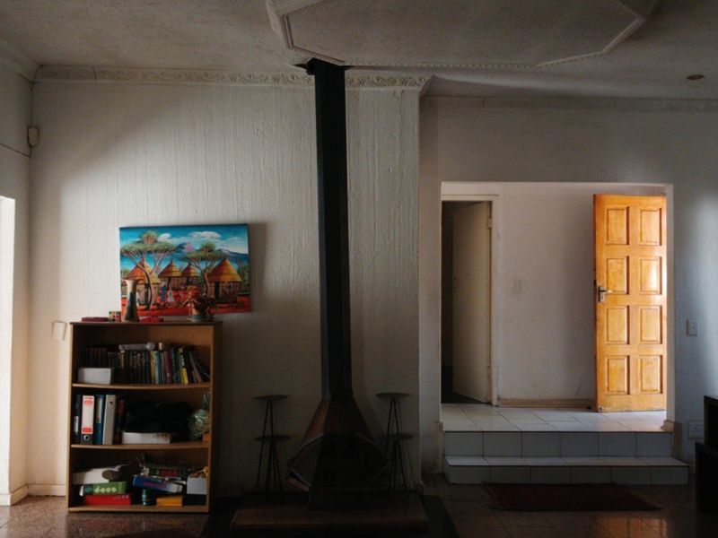 Living room featuring a central freestanding fireplace, tiled flooring, and a raised transition area leading to an adjacent room with a wooden door.