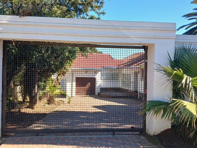Front view of the property featuring a secure gated entrance, paved driveway, and a single garage with a tiled roof.