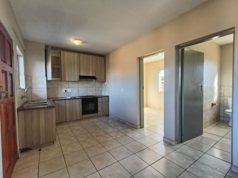 Open plan kitchen area featuring built-in cabinetry, integrated oven, and tiled flooring, with direct access to adjacent rooms.
