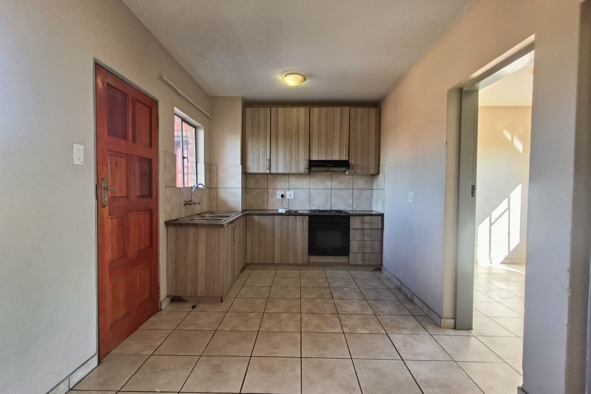 A functional kitchen featuring light wood-tone cabinetry, tiled flooring, a built-in oven, and an extractor fan, offering a clean and practical workspace.