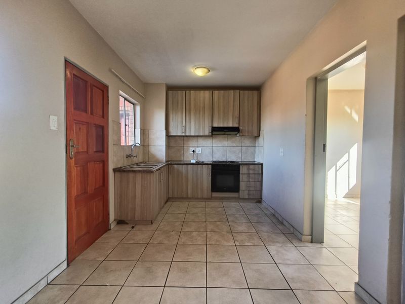 A functional kitchen featuring light wood-tone cabinetry, tiled flooring, a built-in oven, and an extractor fan, offering a clean and practical workspace.