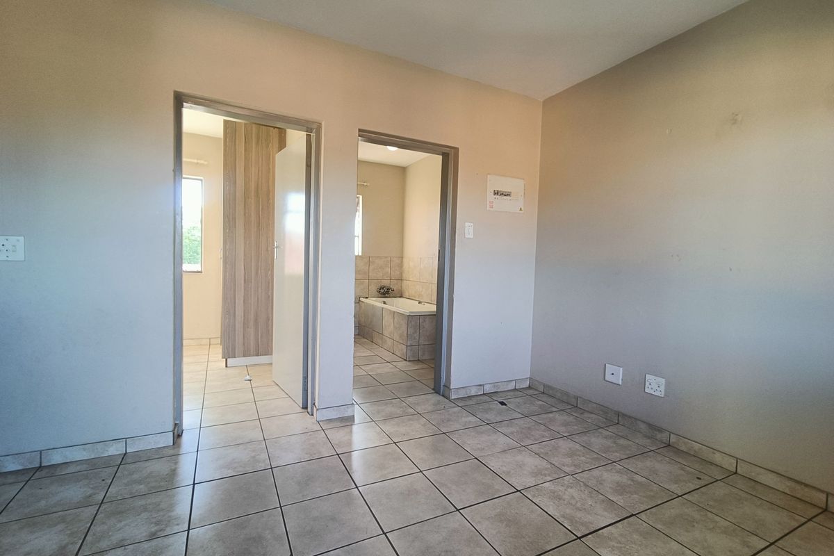 An empty bedroom featuring tiled flooring and direct access to an en-suite bathroom, providing a neutral canvas for personalization.