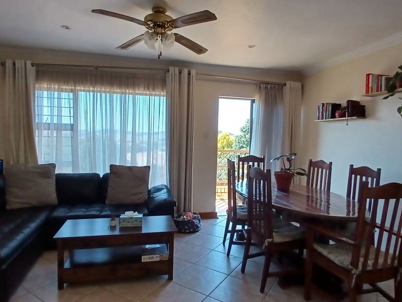 Open-plan living and dining area featuring tiled flooring, a ceiling fan, and direct access to an outdoor balcony through a sliding glass door.