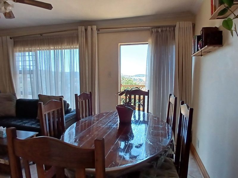 Open-plan living and dining area featuring tiled flooring, crown molding, a ceiling fan, and direct access to an outdoor balcony through a sliding glass door.